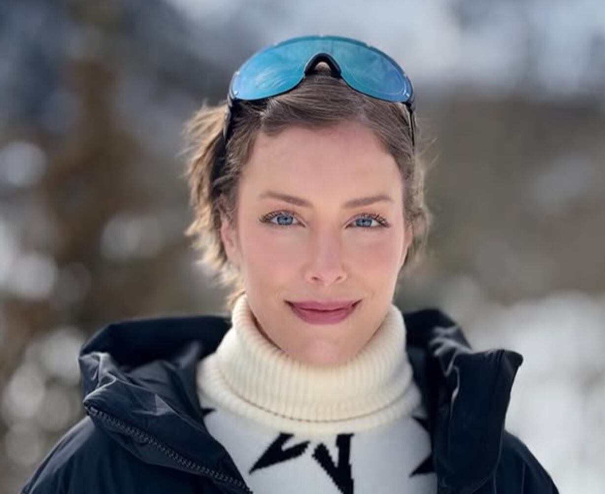 Fabiana Justus está olhando para a câmera. Ela está em um local com neve. É branca, tem os olhos azuis e cabelos curtos castanhos. Usa uma roupa branca e preta e um óculos de neve azul.