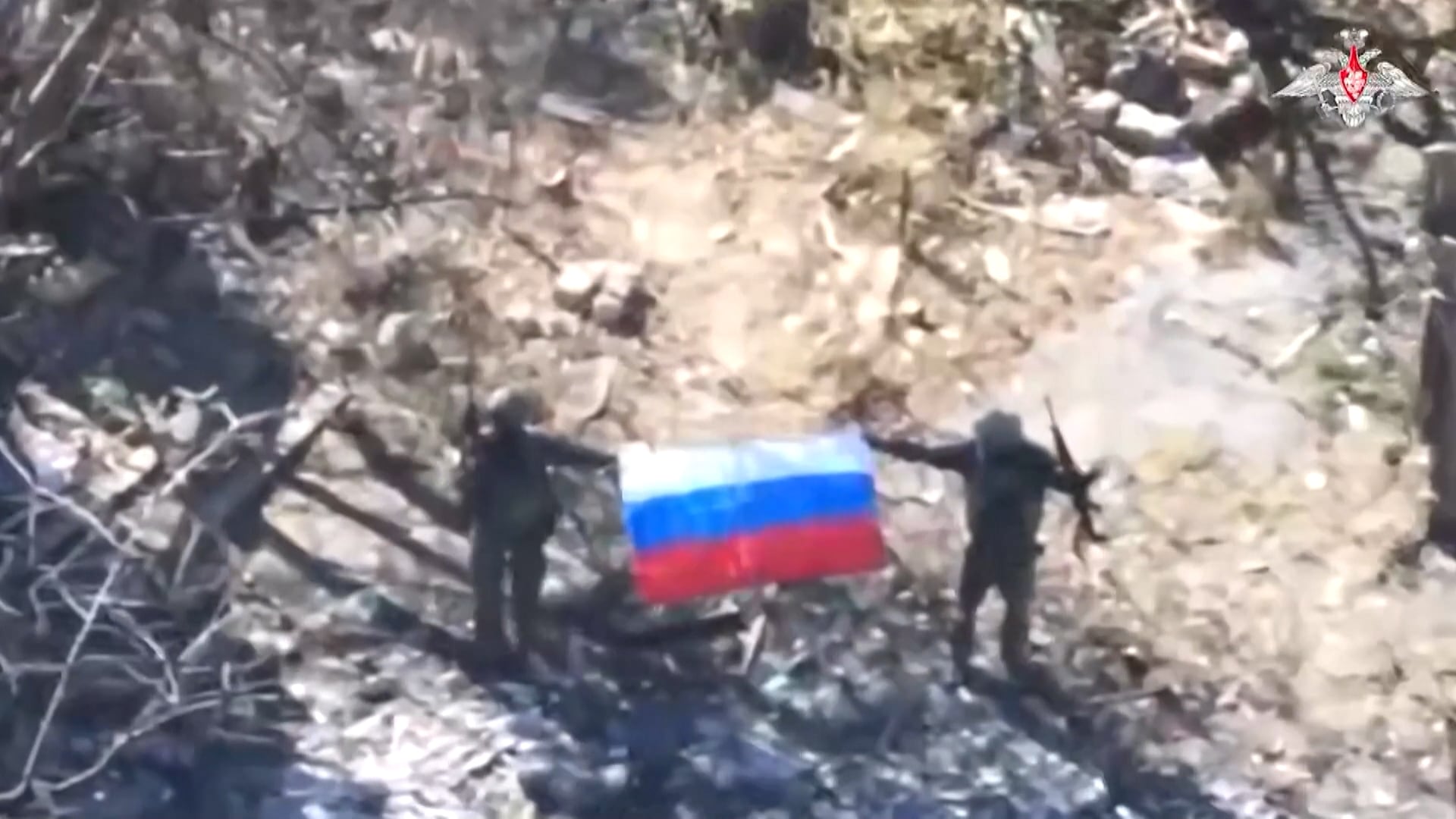 Soldados carregando bandeira da Rússia em um local de destruição e escombros