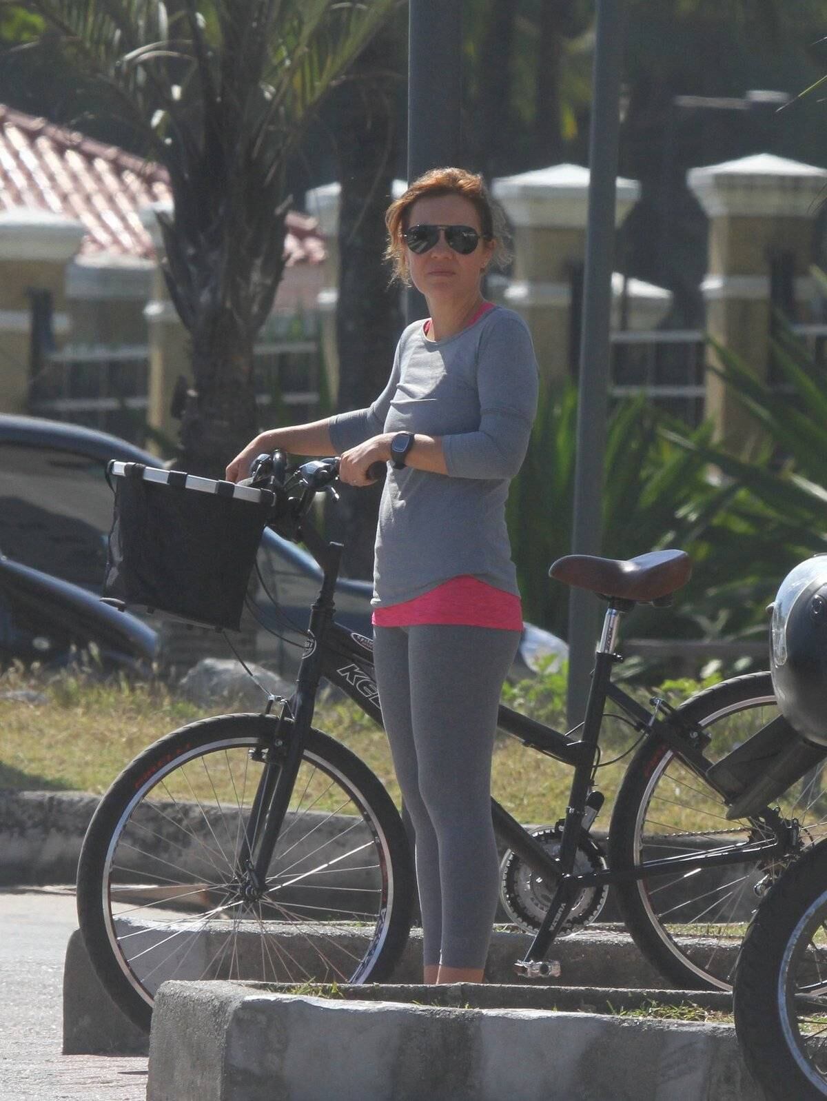 Adriana Esteves e Vladimir Britcha andam de bicicleta na praia da Barra, no Rio