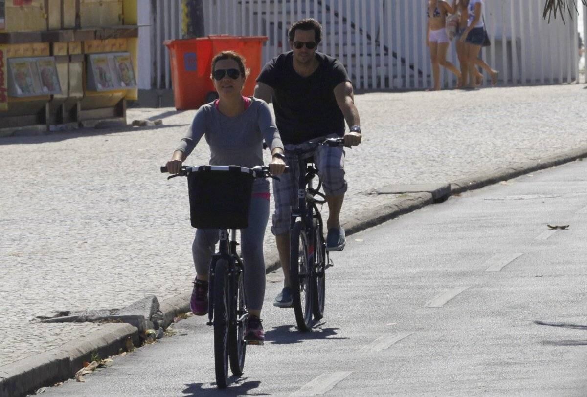 Adriana Esteves e Vladimir Britcha andam de bicicleta na praia da Barra, no Rio
