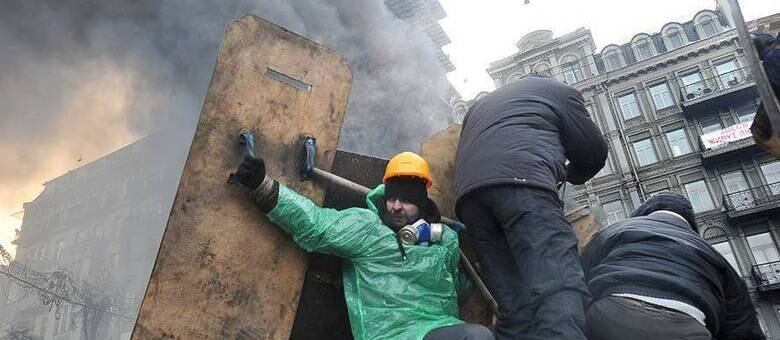 Manifestantes se protegem em barricadas durante confronto com a polícia
