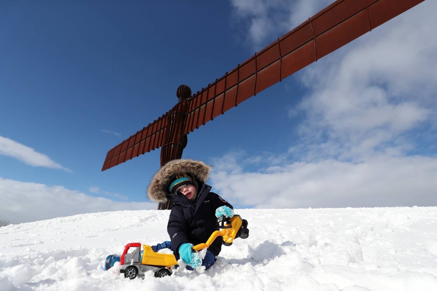 Apesar do frio cortante, esse pequeno bebê decidiu enfrentar a nevasca e foi se divertir com seus brinquedos ao lado da estátua do Anjo do Norte, em Gateshead, no Reino Unido
