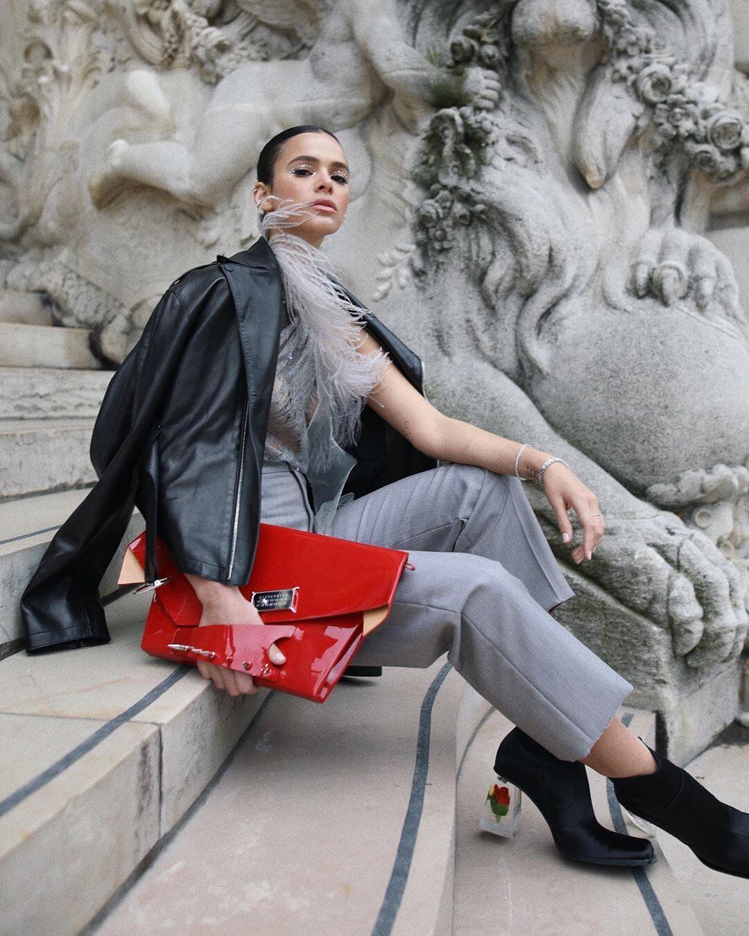 Ela completou o visual com uma clutch vermelha e uma bota de salto transparente