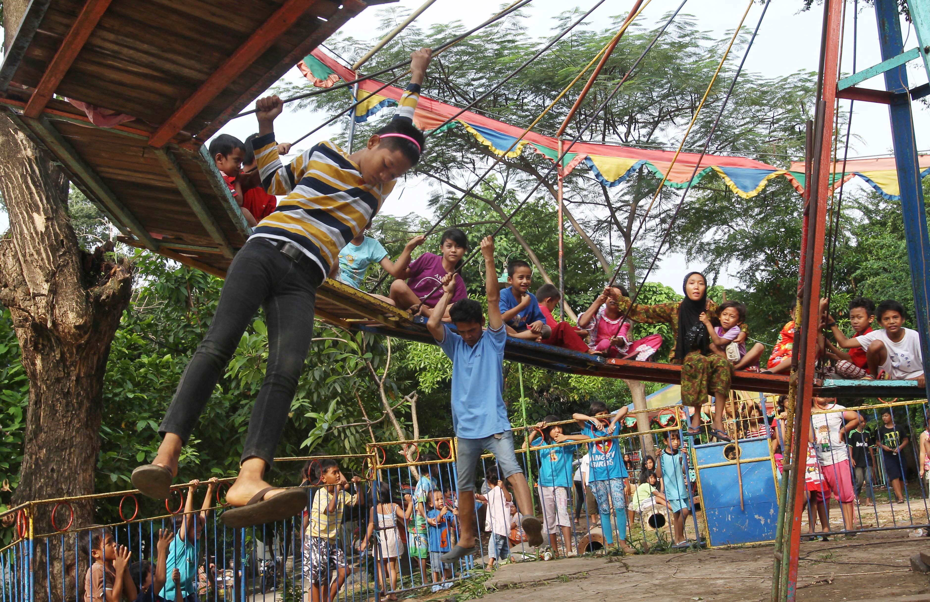 Jovens indonésios brincam em um parque de diversões itinerante em uma favela em Jacarta