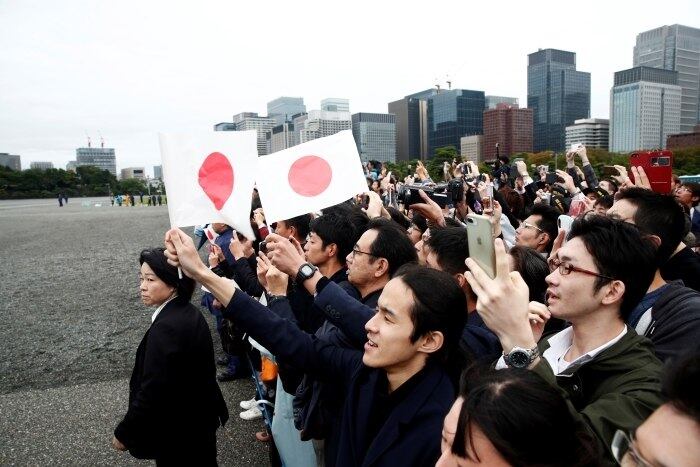Alguns curiosos equipados com guardas-chuvas ficaram do lado de fora do Palácio Imperial para observar a passagem dos carros oficiais e das forças de segurança
