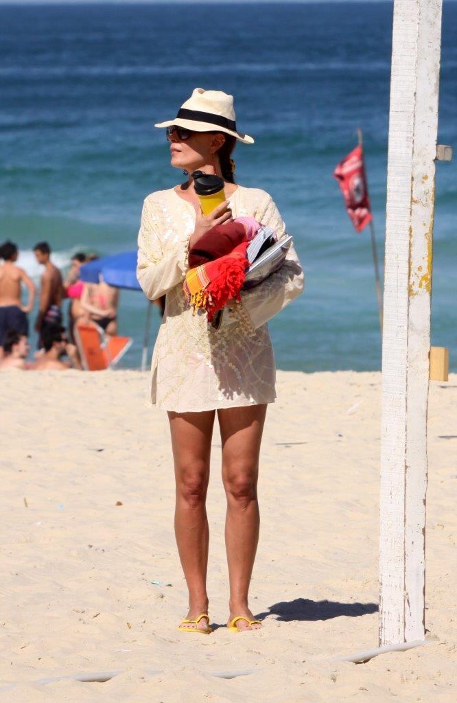 A atriz chegou à praia protegida do sol com chapéu e bata branca