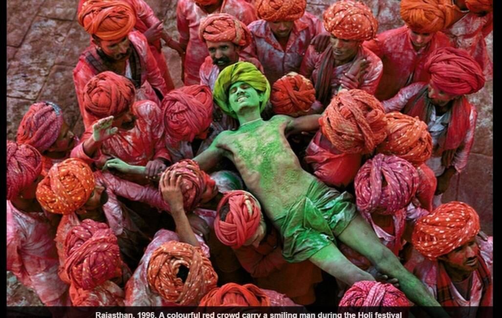 Uma multidão vestida de vermelho carrega um homem pintado de verde durante o festival de Holi, no Rajastão, em 1996