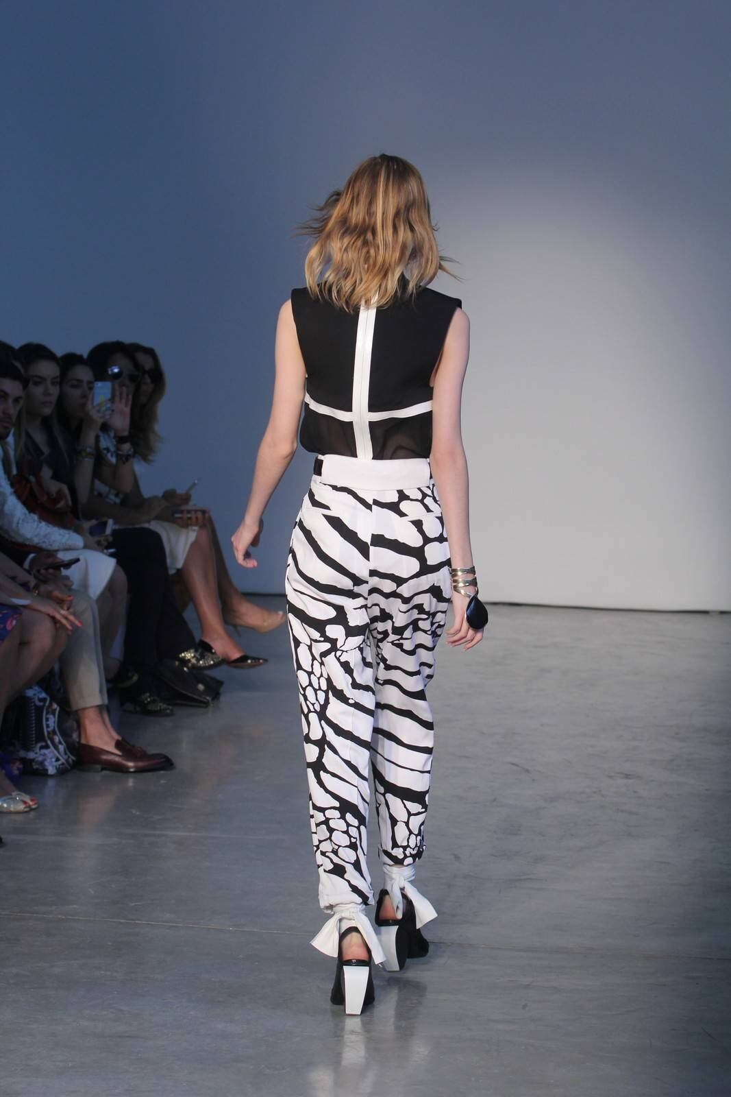 O segundo dia de desfiles da temporada inverno 2015 da São Paulo Fashion Week começou com a coleção do estilista Pedro Lourenço, nesta terça-feira (4). As modelos entraram na passarela após uma hora de atraso e vestiram peças feitas de diferentes materiais, que iam desde os trabalhos com paetês até detalhes com argolas de meta. Além dos casacos e saias que deram um ar sexy à coleção, as sandálias com saltos largos, arredondados e amarrações no tornozelo também foram destaque na passarela