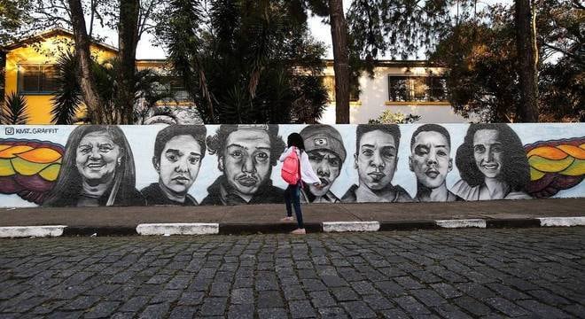 Pintura reproduz os rostos das vítimas do massacre sobre o muro branco