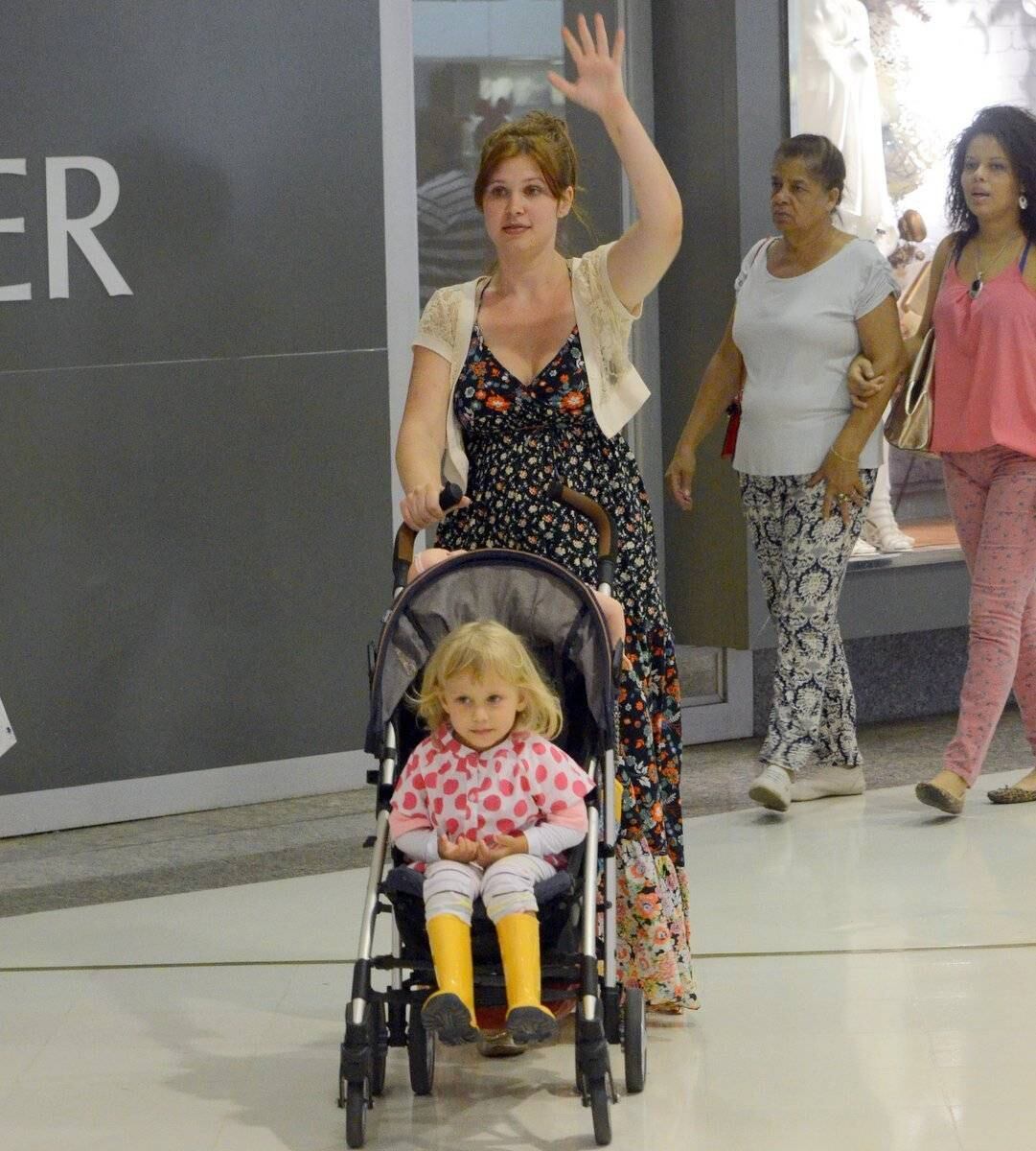 A atriz passei e acena para alguém no shopping
