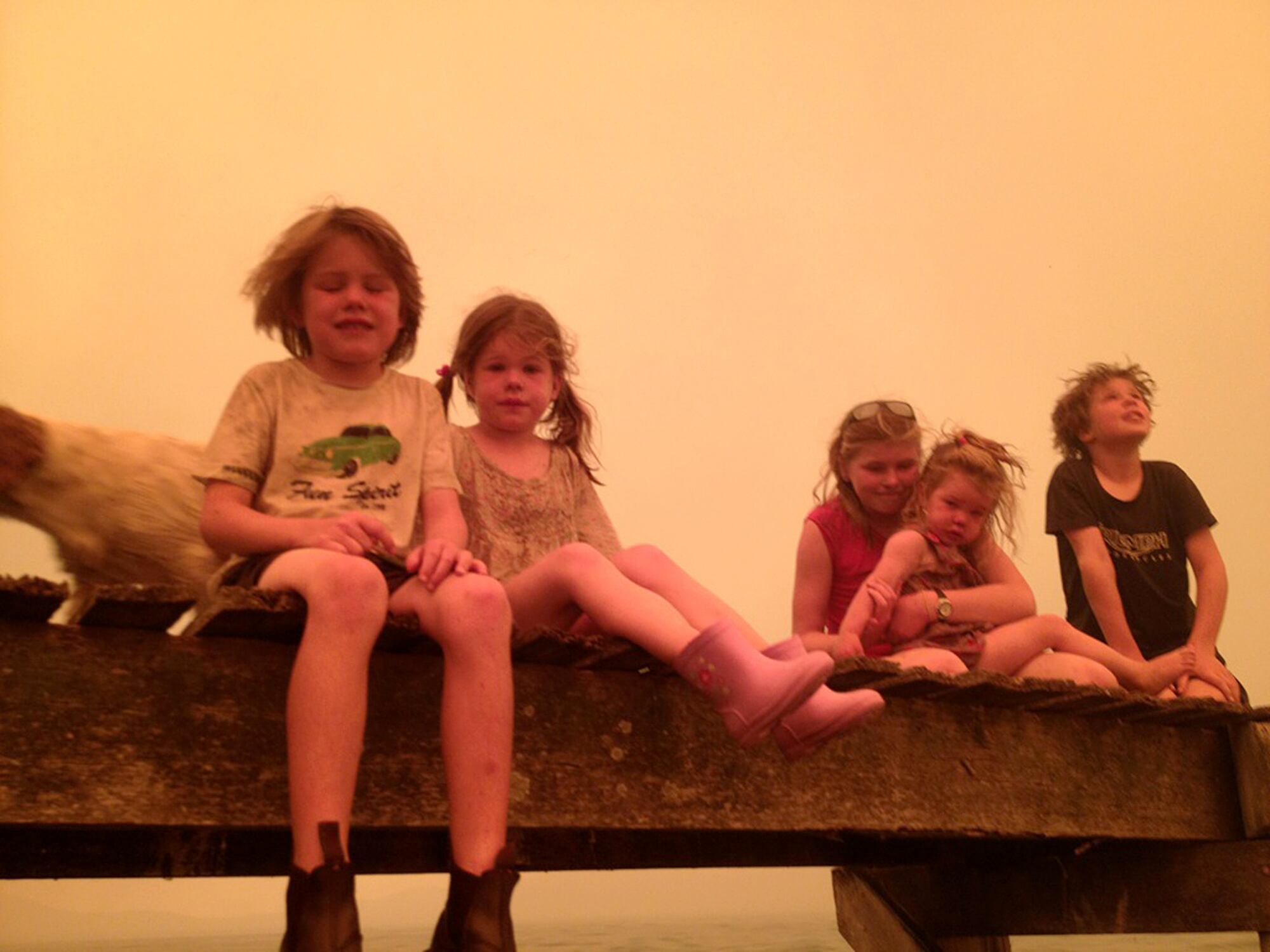 Caleb, de 6 anos, Esther, de 4, Matilda, de 11, Charlotte, de 2, e Liam, de 9, aguardam o momento de pular na água junto a seus avós. Ao lado das crianças, o cachorro Polly, que também escapou do fogo