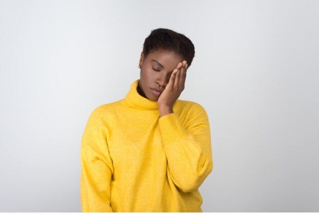 Jovem negra com as mãos no rosto, aparentando cansaço