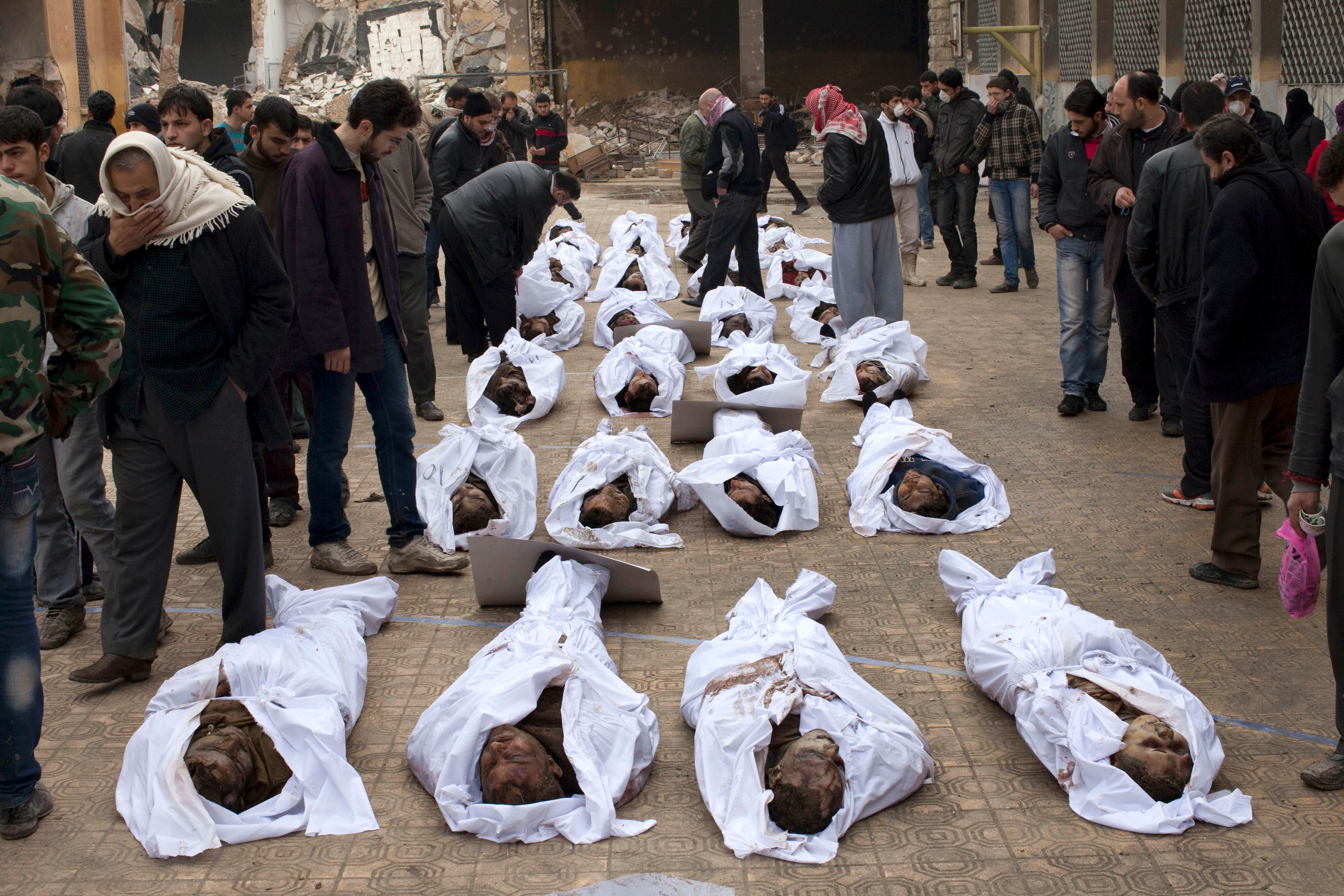 Sírios procuram por parentes entre os corpos de homens executados e jogados no rio Quweiq, em Aleppo