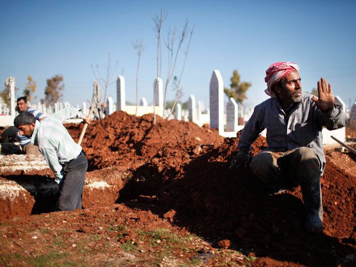 Coveiros de cemitério da cidade de Azaz, no norte da Síria, não esperam mais bombas caírem para começarem a cavar