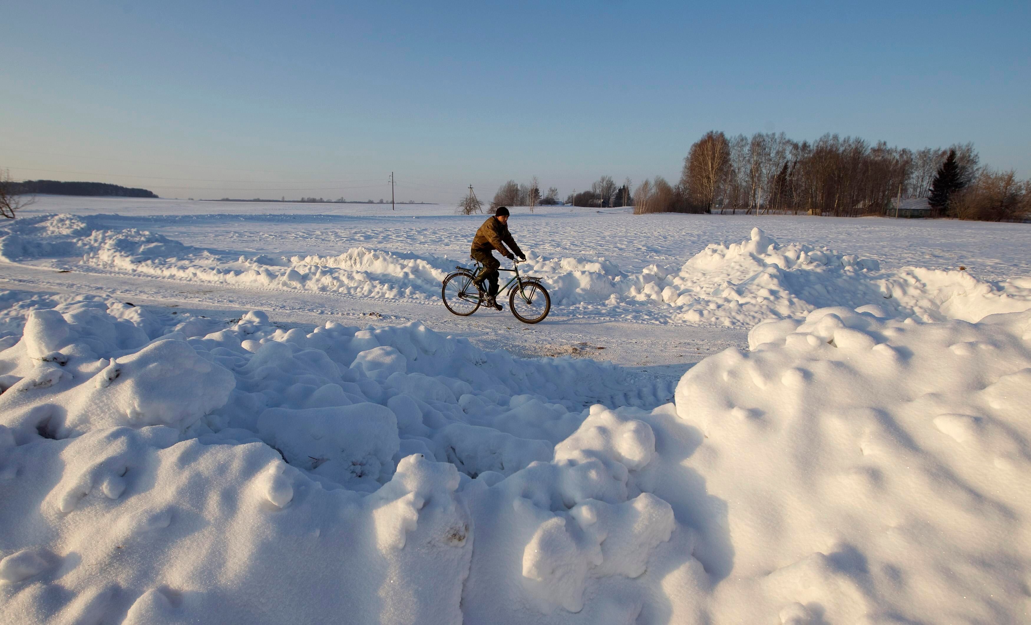 Homem anda de bicicleta pela neve, no vilarejo de Raklevichi, em Minsk, Bielorrússia. A temperatura na região, neste domingo (22) , é de -19°