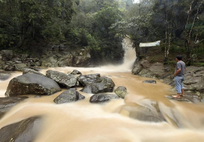Homem observa a cascata de um rio poluído em Bogor, Indonésia. O rio Citarum, localizado no país, é conhecido como o mais poluído do mundo