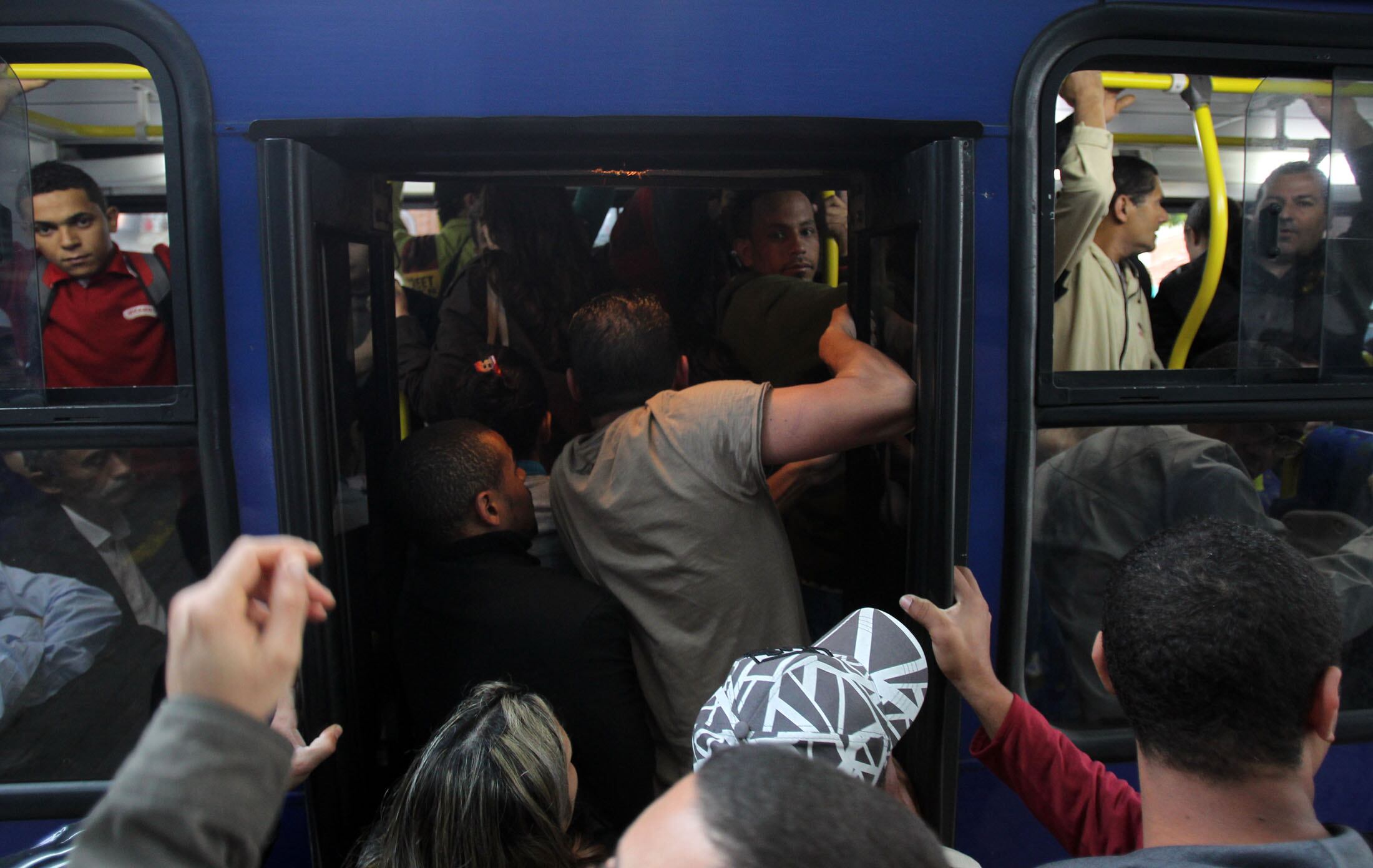 Passageiros embarcam em ônibus lotado na avenida Brasil, entre as estações Ferraz de Vasconcelos e Poá da CPTM
