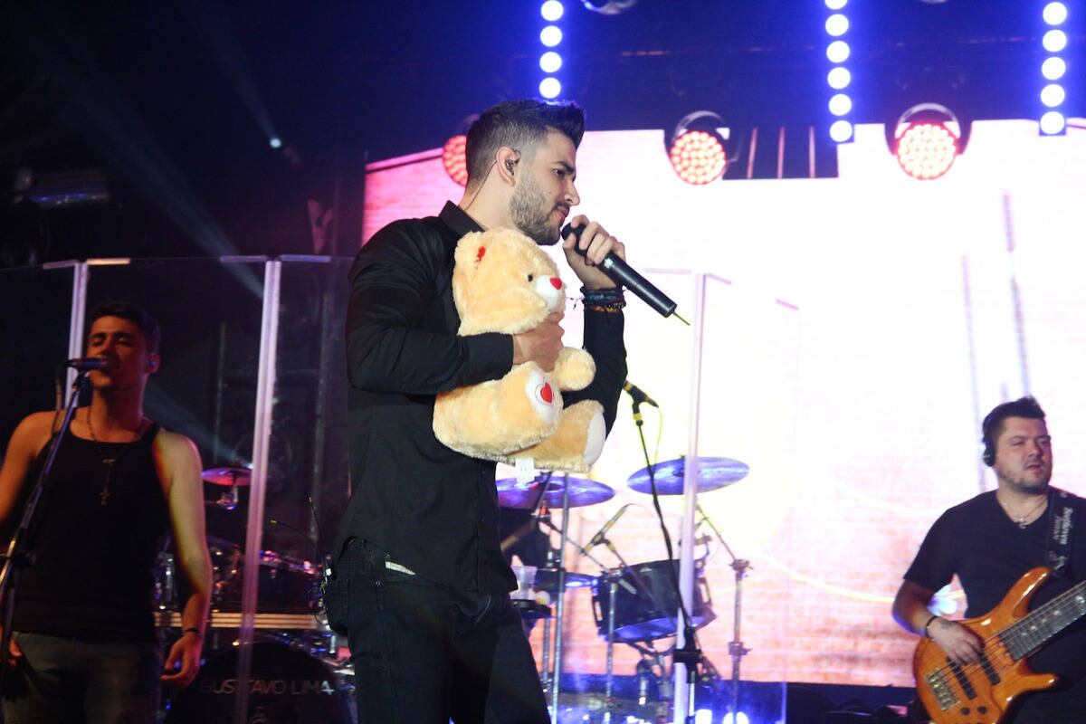 Gusttavo Lima canta segurando um dos presentes que foi lançado pelos fãs