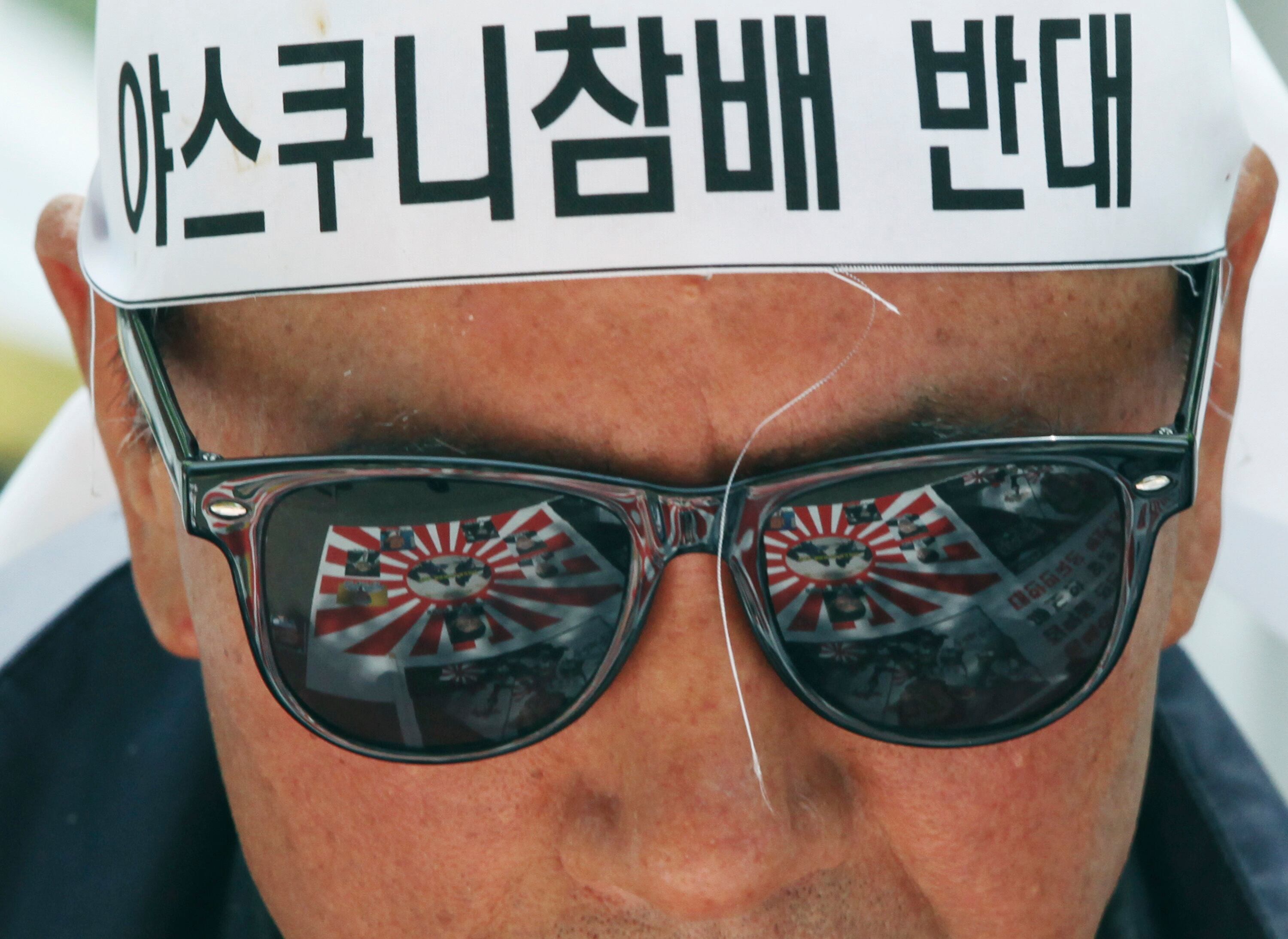 Bandeiras de guerra japonesas são refletidas no óculos de sol de um manifestante durante comício contra o Japão, em frente a residência do embaixador do país em Seul, na Coreia do Sul. 

Os manifestantes são contrários às declarações do prefeito de Osaka de que prostituras eram necessárias para "manter a disciplina" durante a Segunda Guerra Mundial
