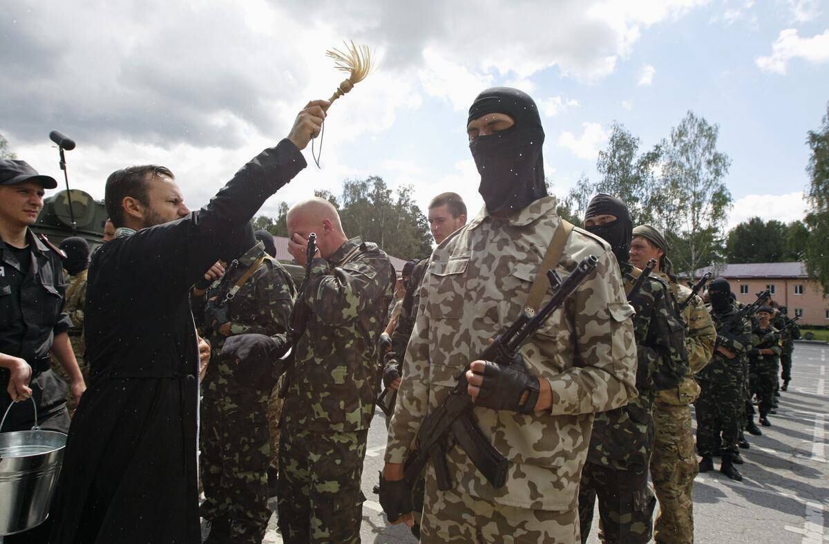 Um padre benze os membros do grupo de autodefesa "Donbass", na Ucrânia, durante a cerimônia de juramento à Guarda Nacional