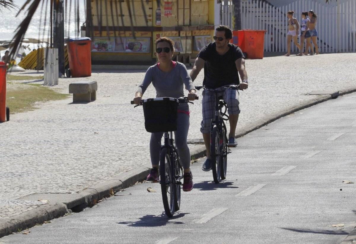Adriana Esteves e Vladimir Britcha andam de bicicleta na praia da Barra, no Rio