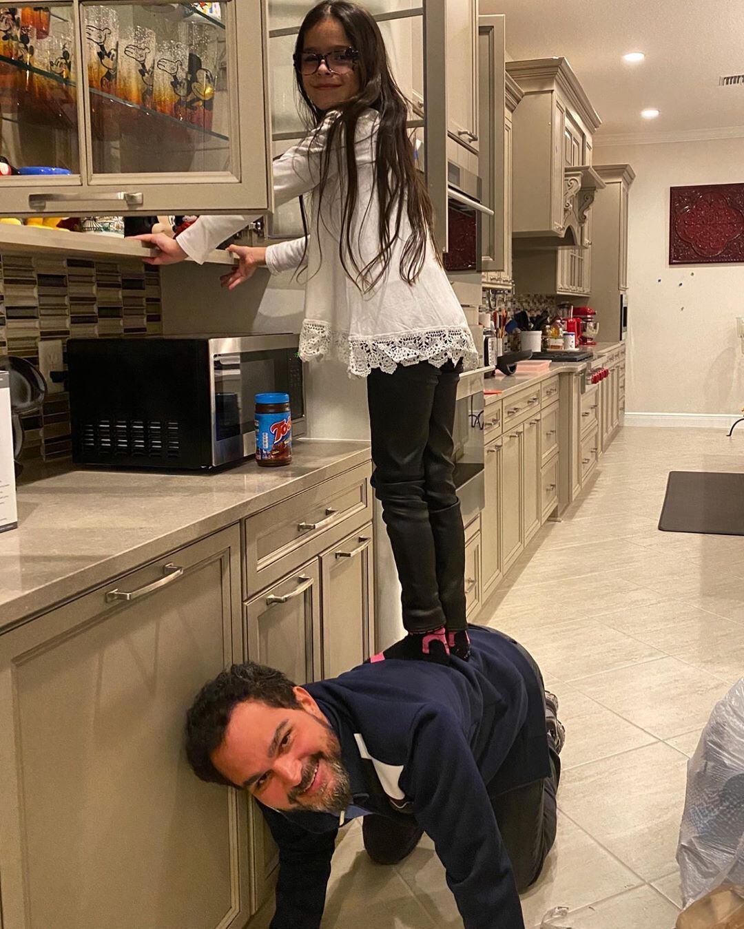 Sempre brincalhão, Luciano serviu de 'escada' para uma das filhas gêmeas alcançar a louça da cozinha. "Papai... faz leite com toddy? Só se você pegar a caneca... tá bom... eu pego, vida dura de pai né?"