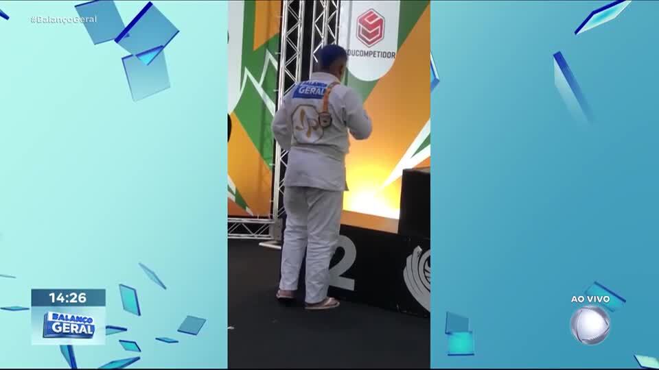 Jovem lutador de jiu-jitsu sobe em pódio de campeonato usando quimono do Balanço Geral