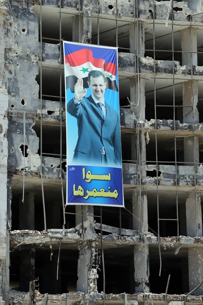 Um cartaz com a imagem
do presidente sírio Bashar al-Assad é visto em um edifício destruído em Homs. No
cartaz, está escrito em árabe “Nós construiremos juntos”. As eleições presidenciais
no país começam hoje