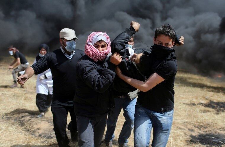 Palestinos carregam homem ferido em confronto