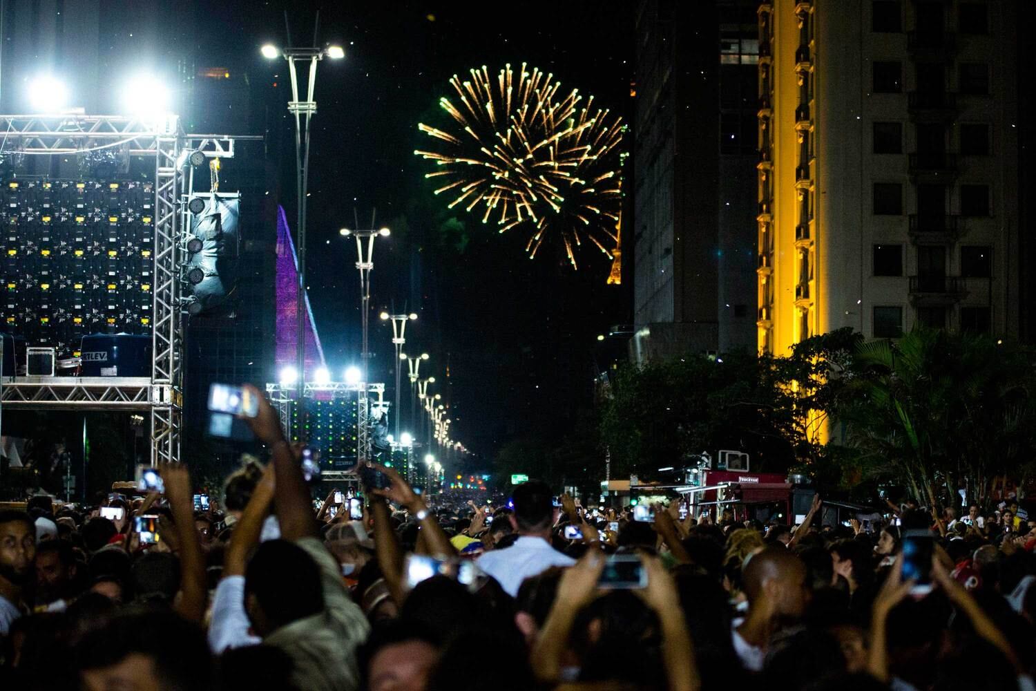 Pessoas assistem e registram a queima de fogos da virada do ano na Avenida Paulista