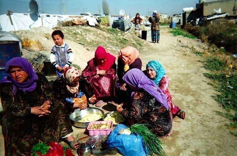 Em um dia ensolarado, um grupo de mulheres se preparam para uma refeição