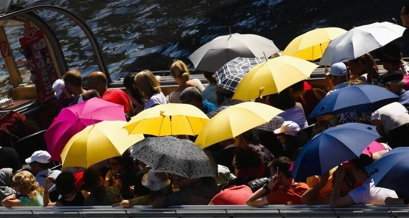 Turistas usam
guarda-chuvas para se proteger do sol durante passeio de barco no rio Spree, em
Berlim, capital da Alemanha